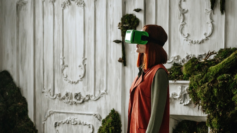 Frau mit VR-Brille in einem historischen Raum mit Moosbewuchs
