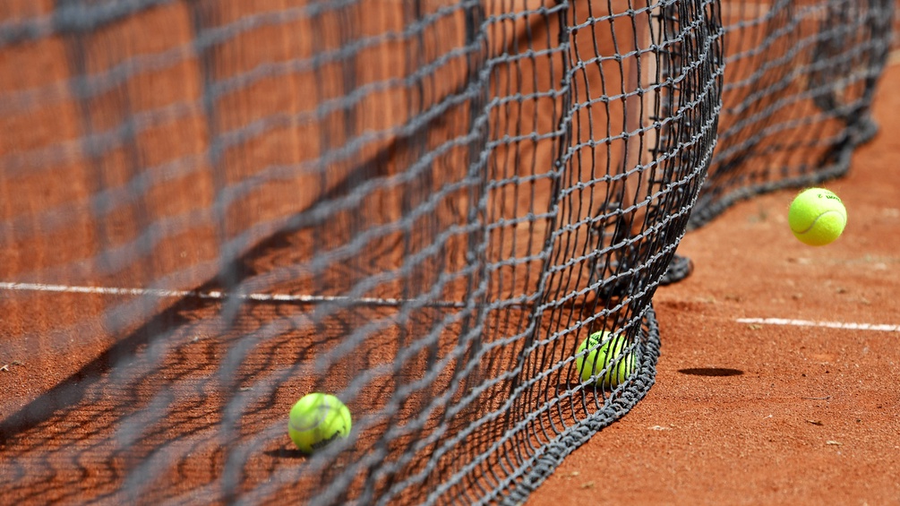 Tennisbälle verfangen sich im Netz.