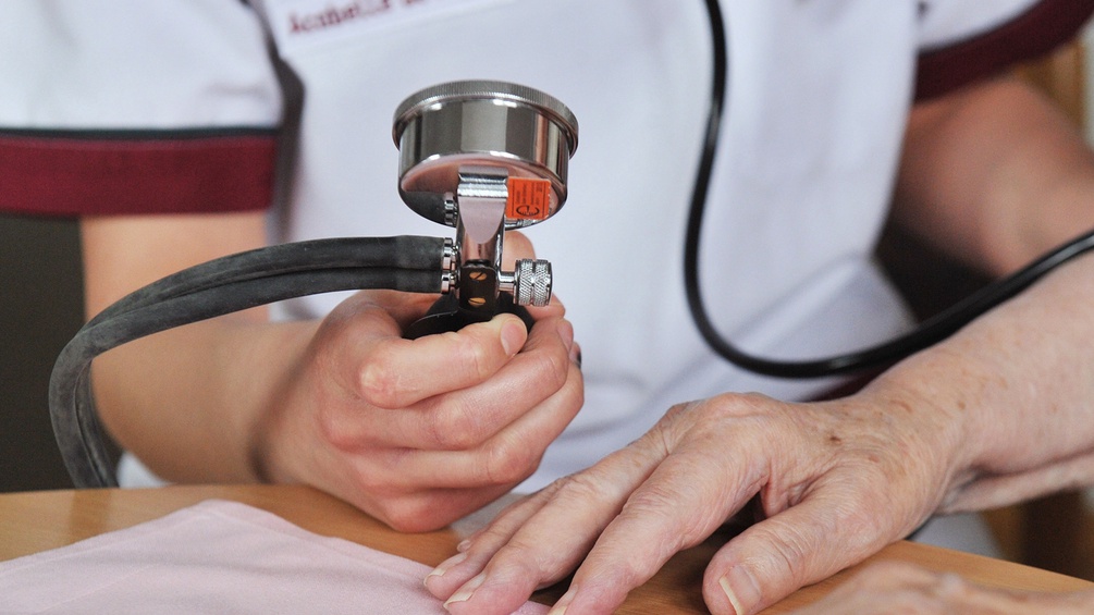Krankenpflegerin misst bei Patientin Blutdruck