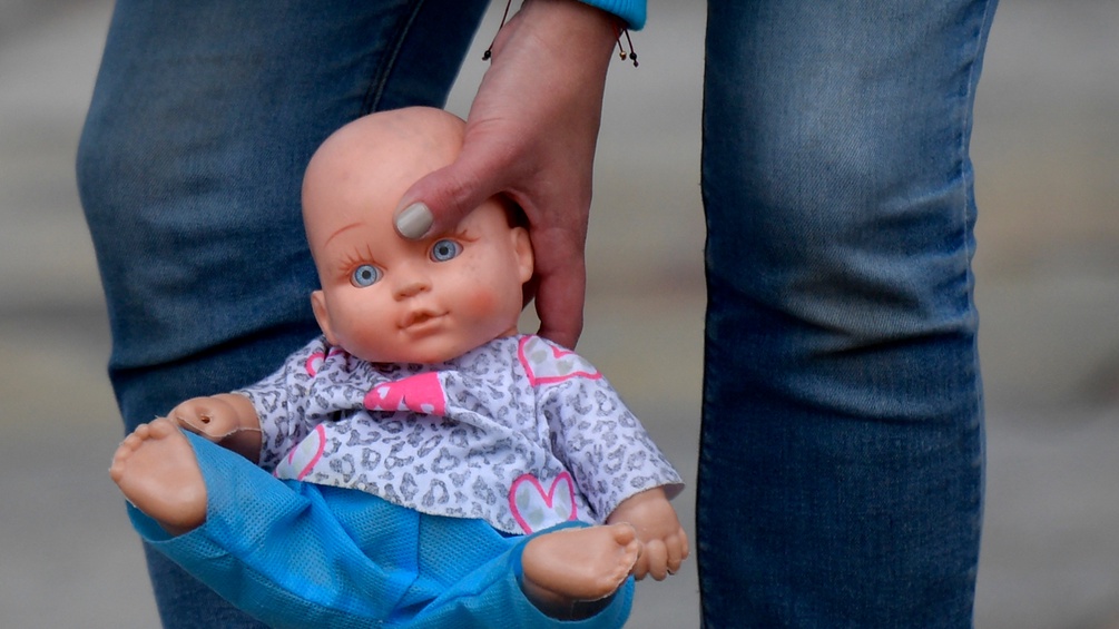 Ein Kind hält eine Puppe in der Hand.