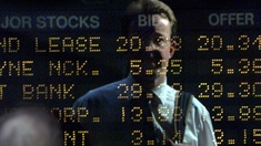 Ein Mann steht vor einem Screen mit Börsenanzeigen