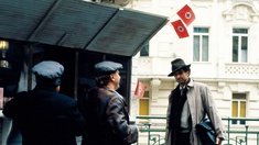 Szene aus dem Film "38 - Auch das war Wien": Protagonist steht vor einem Würstelstand, von dem Hakenkreuzfahnen wehen.