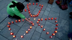 Eine Frau zündet Kerzen an in Form des Symbols für Atomkraft.