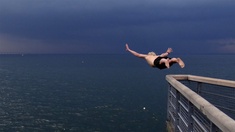 Ein Mann springt von hoch oben ins Meer