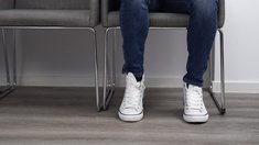Mann sitzt in einem Wartezimmer, weiße Converse