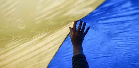 Eine Hand berührt die Ukrainische Fahne