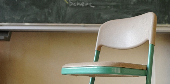 Ein leerer Sessel vor einer Tafel in einer Schulklasse
