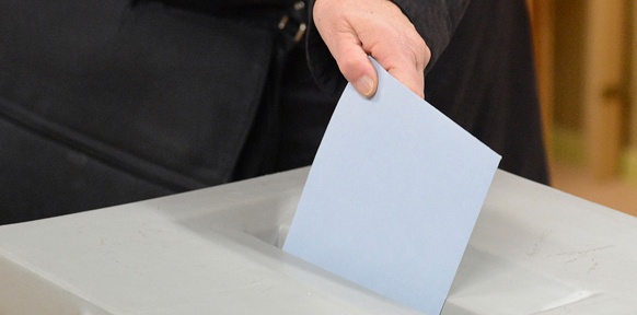 Stimmzettel wird in die Wahlurne geworfen
