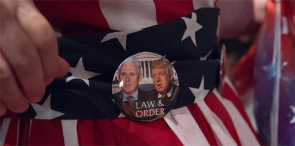 APA/AFP/MOLLY RILEY Ein Button mit der Aufschrift "Law & Order" und dem Gesicht vom Trump ist auf eine US-Flagge gesteckt.