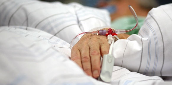 Die Hand eines Kranken mit Venflow im Spitalsbett