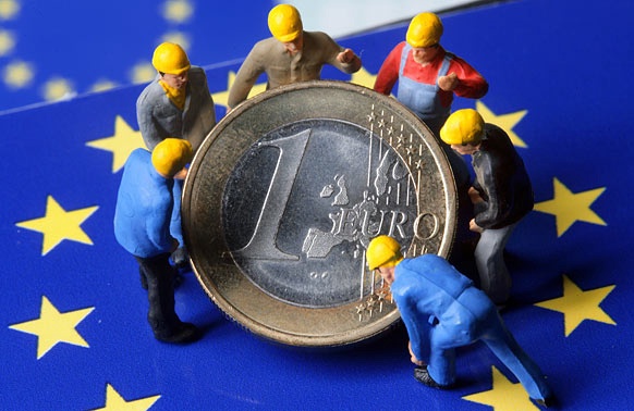 Spielzeugarbeiter heben eine Euromünze an