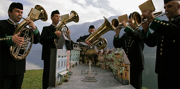 Musiker spielen vor dem Modell eines Dorfplatzes