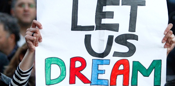 Eine Frau hält ein Plakat auf dem "Let us dream" steht