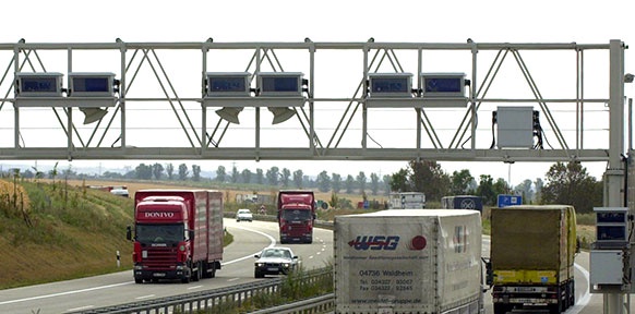 LKWs fahren auf der Autobahn unter einer Mautstelle durch