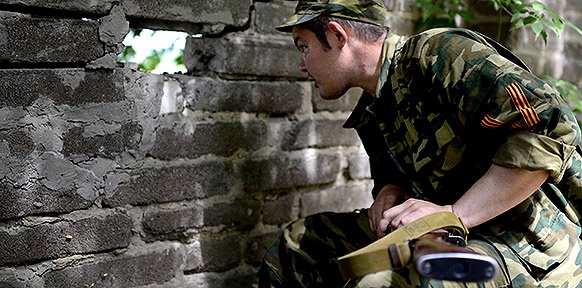 Ein Soldat schaut durch ein Loch in einer Mauer