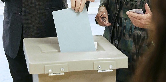 Ein Stimmzettel wird in eine Wahlurne geworfen