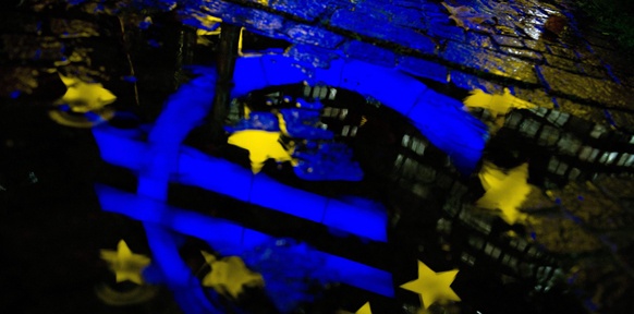 Das Eurozeichen spiegelt sich in einer Wasserpfütze