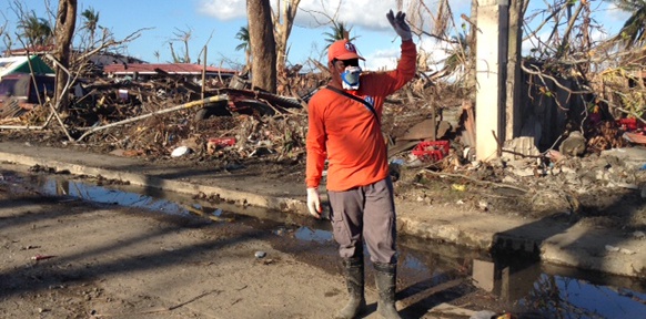 Mann mit Schutzmaske inmitten zerstörter Häuser