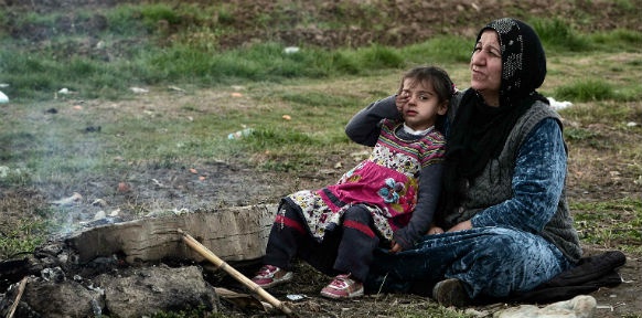 Erschöpftes Kind sitzt mit Großmutter in einem Flüchtlingscamp nahe dem Dorf Idomeni