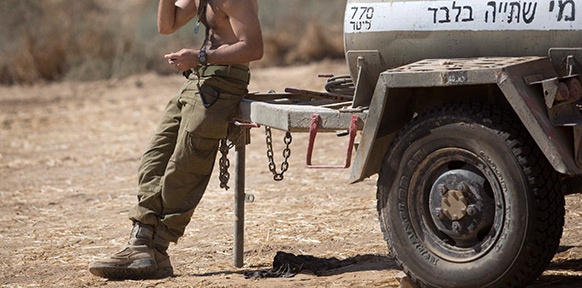 Israelischer Soldat lehnt an Wassertank