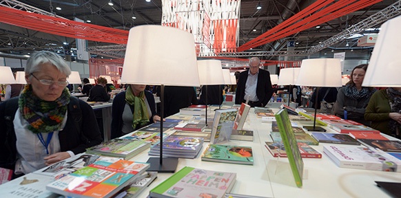 Besucher auf der Leipziger Buchmesse betrachten ausgestellte Bücher