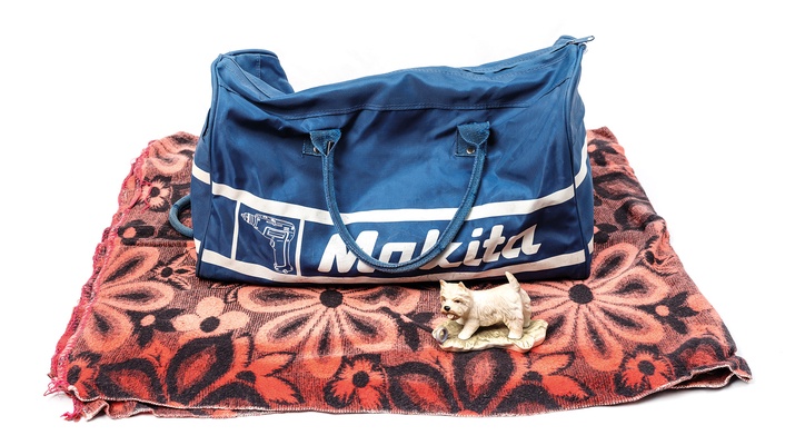 Blaue Tasche mit der Aufschrift "Makita" auf einer geblümten Decke.