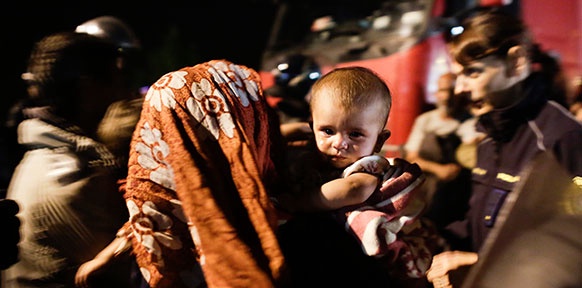 Eine Frau mit Koptuch hält im Tumult ihr Baby