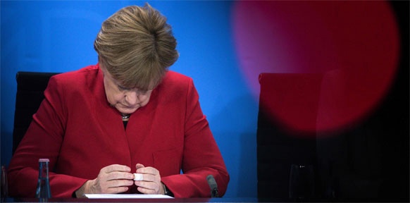 APA/AFP/DPA/BERND VON JUTRCZENKA Angela Merkel sitzt an einem Tisch und schaut sehr betreten auf ihre Hände.