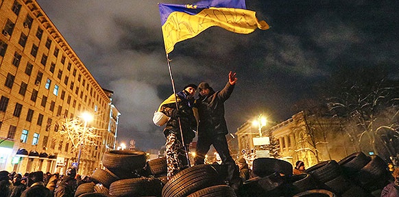 Ukrainische Demonstranten stehen auf einer Barrikade und schwenken die Ukrainische Flagge