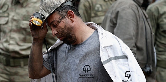 Traurig wirkender Minenarbeiter greift zum Helm