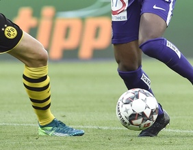 Die Beine von zwei Fußballspielern und ein Ball.
