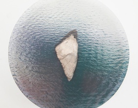 Kunstinstallation mit einem Stein auf einer Glasplatte als Insel