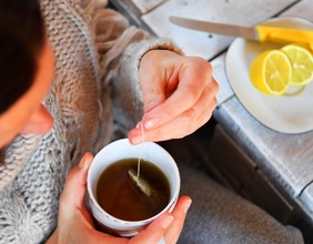 Eine Frau sitzt am Tisch mit Tee und Zitronen