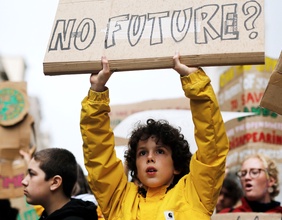 Ein Junge hält ein Schild mit der Aufschrift "No Future?" in die Luft