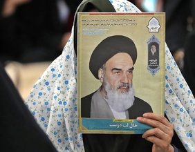 Eine Frau hält ein Bild von Ayatollah Ruhollah Khomeini