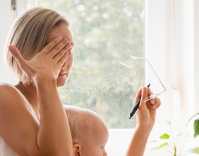Gestresst wirkende Frau mit Kleinkind und Brille