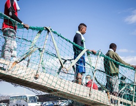 Migranten gehen über Bootssteg