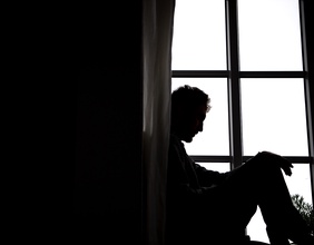 Ein Mann sitzt an einem Fenster.