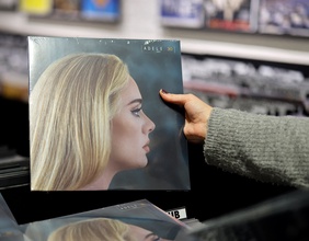 Eine Frau hält das Plattencover von Adele hoch.
