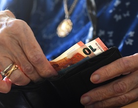 Ein Pensionistin öffnet ihre Geldbörse