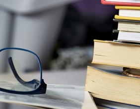 Brille neben Bücherstapel