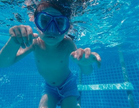 Tauchendes, schwimmendes Kind in einem Schwimmbecken