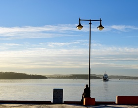 Mann sitzt am Osloer Hafen