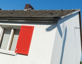 Weißes Haus mit roten Fensterläden
