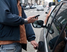 Car sharing: Mann mit Smartphone öffnet Auto