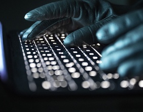 Hände in Handschuhen auf der Tastatur 