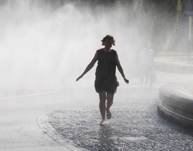 Frau kühlt sich bei Wasserdusche am Schwarzenbergplatz in Wien ab