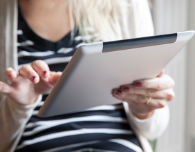 Frau hält ein Tablet und liest