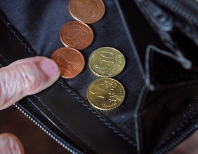 Finger einer alten Dame und eine geöffnete Geldbörse, Münzen, Pension