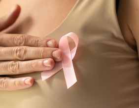Weltbrustkrebstag: Frau hält rosa Masche an den Oberkörper